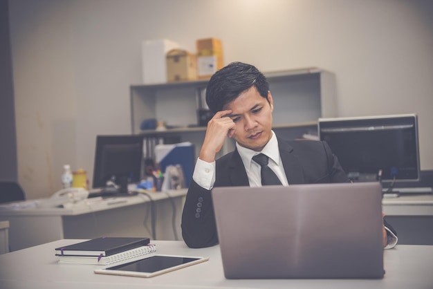 Stress da uomo d'affari da duro lavoro sulla scrivania in ufficio tono scuro