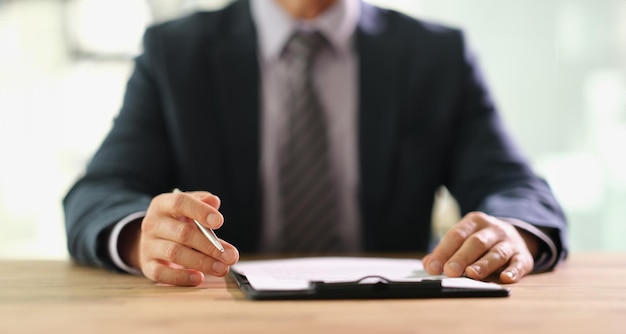 Businessman studying information on document before signing at work in office closeup