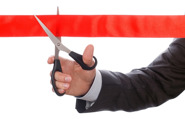 Photo businessman in suit cutting red ribbon with pair of scissors