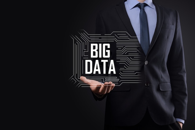 Businessman in a suit on a dark background holds the inscription BIG DATA. Storage Network Online Server Concept.Social network or business analytics representation