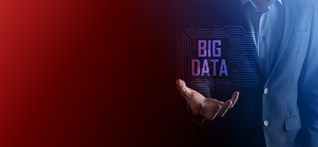 Businessman in a suit on a dark background holds the inscription BIG DATA