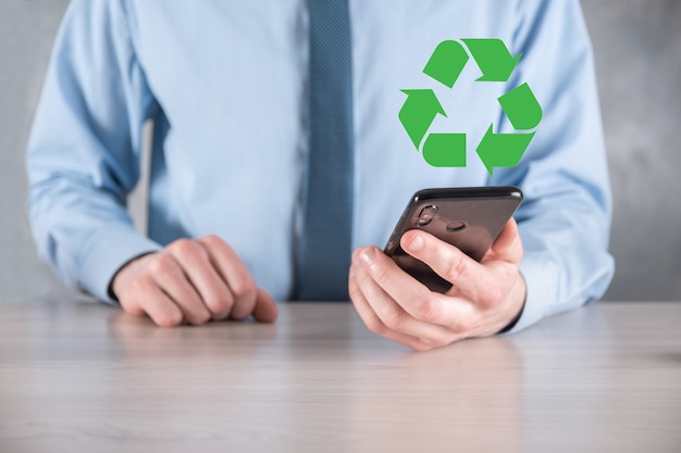 Businessman in suit over dark background holds an recycling\
icon, sign in his hands. ecology, environment and conservation\
concept. neon red blue light.