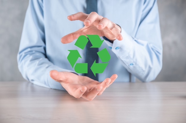 Businessman in suit over dark background holds an recycling icon