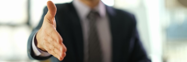 Businessman in suit extending his hand for handshake or greeting closeup