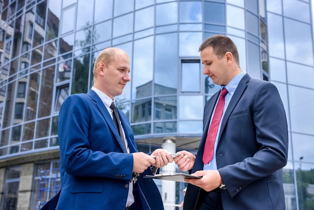 Businessman in suit giving dollar banknotes to another