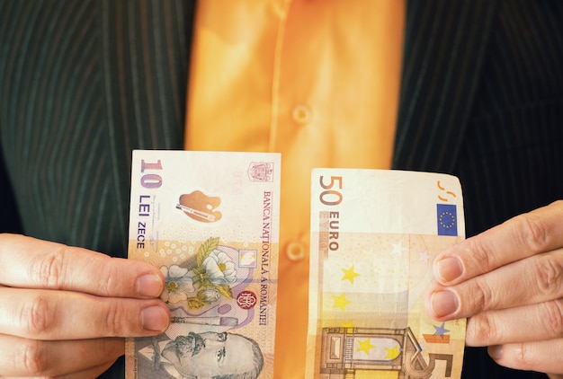 Businessman in suit holding Romanian lei and Euros