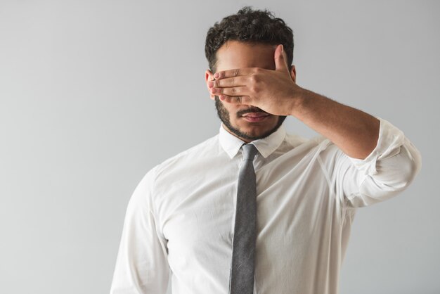 Businessman in suit is covering his eyes