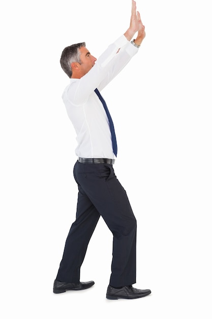 Businessman in suit looking up and pushing