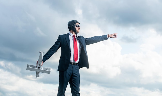 Businessman in suit and pilot hat launch plane toy on sky background startup