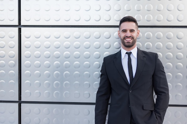 Businessman in suit at silver building wall