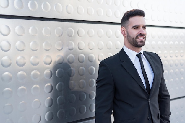 Businessman in suit at silver building wall