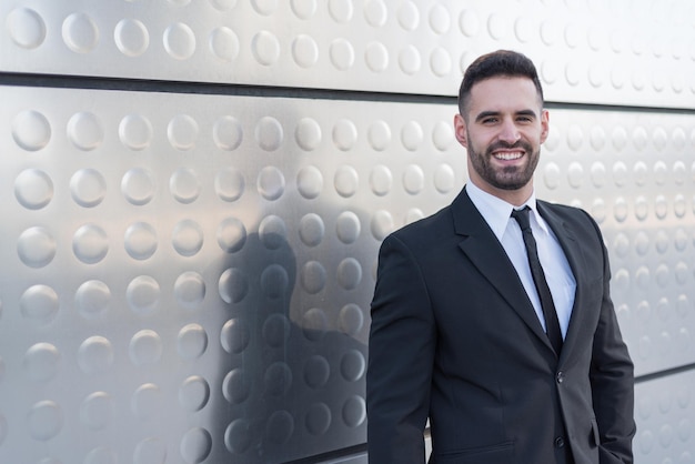 Businessman in suit at silver building wall