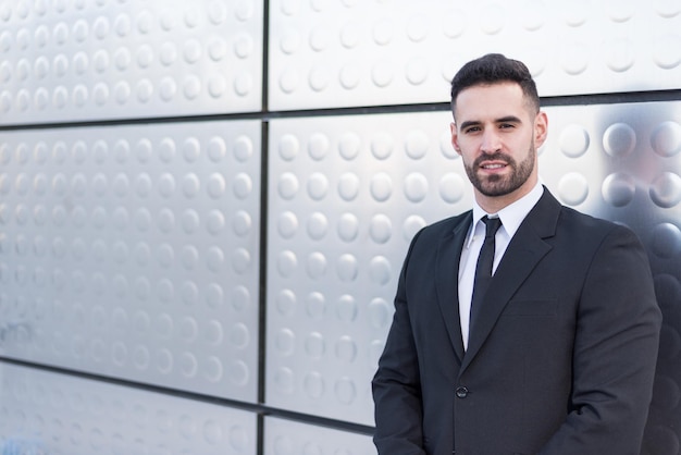 Businessman in suit at silver building wall