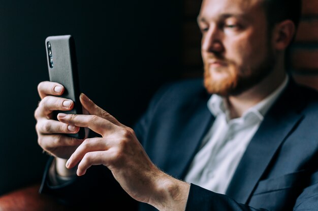 Businessman in a suit sitting in a chair with a smartphone and talking on the video connection.