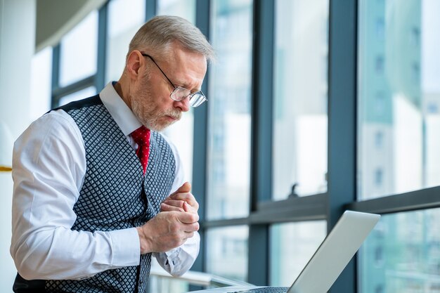 Businessman in suit. Sitting with a laptop near the window.