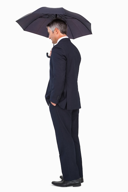 Businessman in suit standing under umbrella