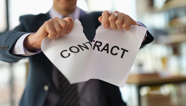 Businessman in suit tearing paper document contract at work in office closeup