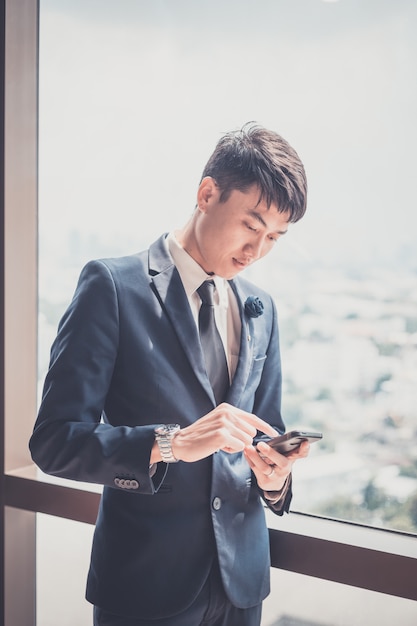 Businessman in suit and using modern smartphone in his office. concept for business