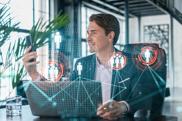 Businessman in suit using smart phone to check new candidates for international business consulting HR social media icons over modern panoramic office background