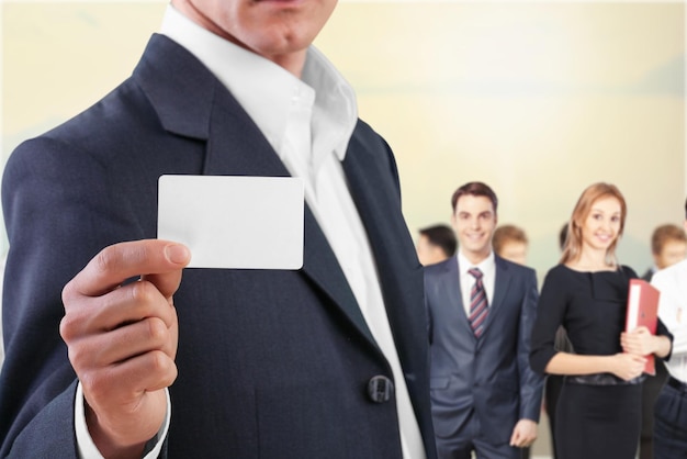 Businessman in suit with card on office background