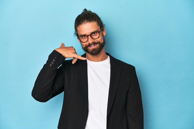 Businessman in suit with eyeglasses and beard showing a mobile phone call gesture with fingers