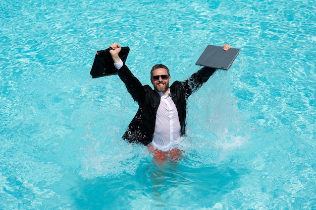 Businessman in suit with laptop in swimming pool crazy business man on summer vacation excited busin