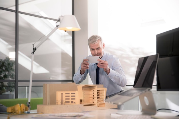 Businessman taking pictures of architectural model