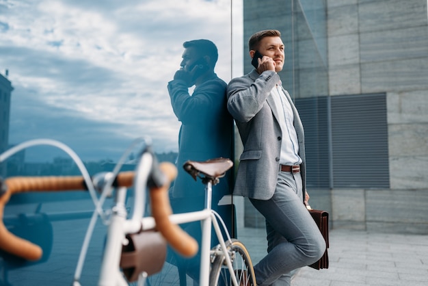 Businessman talking by mobile phone at the bicycle