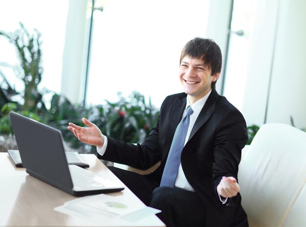 Businessman talking to colleague sitting at his desk