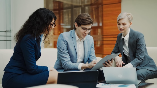 Businessman talking and duscussing future contract with female business partners sitting on couch