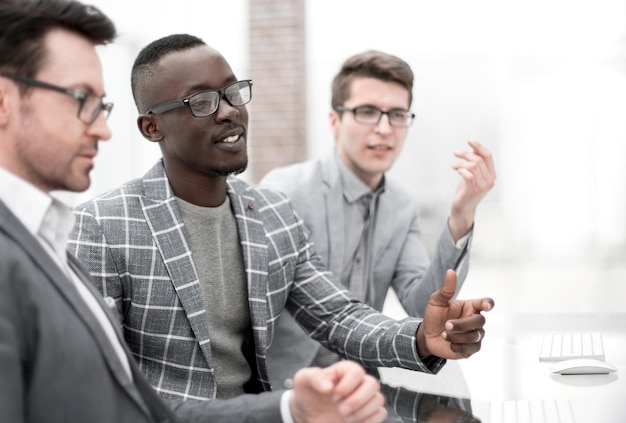 Businessman talking to employees and sitting behind a Desk