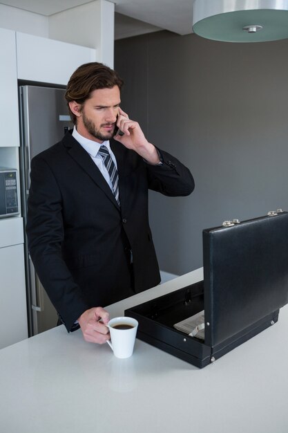 Businessman talking on mobile phone in kitchen