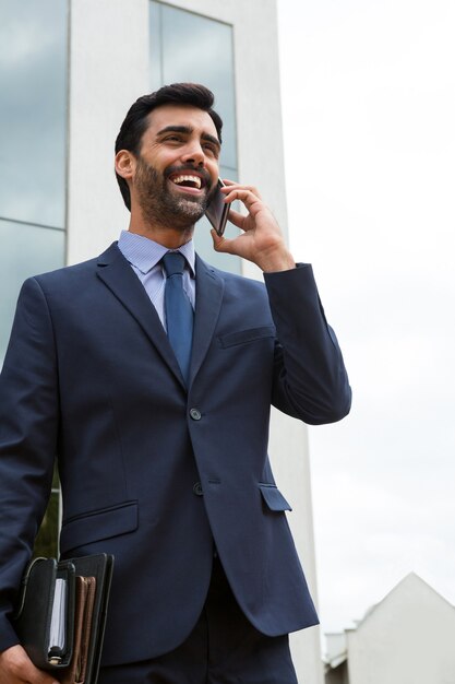 Businessman talking on mobile phone near office building