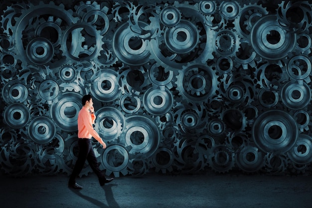 Businessman talking on the mobile phone with cog wheels background