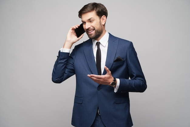 Businessman talking on the phone over grey wall