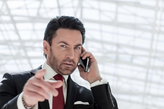 Businessman talking on the phone and pointing at you