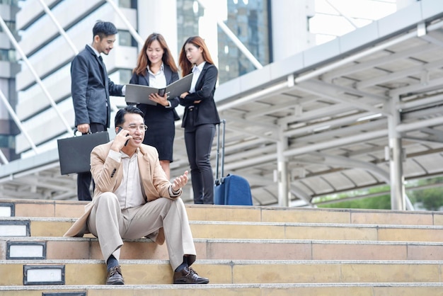 同僚が背景で議論している間ビジネスマンが電話で話している