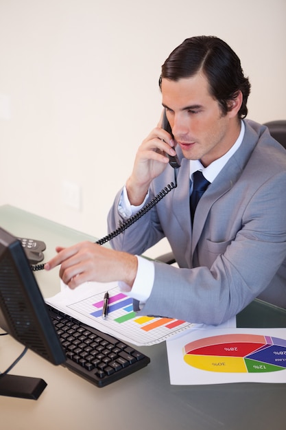 Бизнесмен говорить по телефону во время работы по статистике