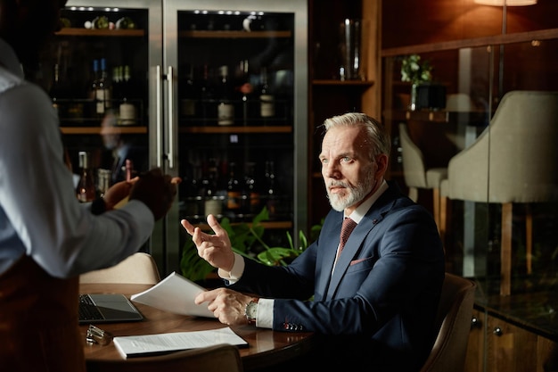 Businessman talking to waiter at lunch time in cafe