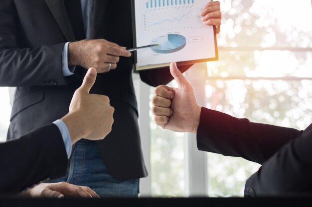 Businessman talking with colleagues show thumb about finance and success of company as presentation conceptt as teamwork and team of business