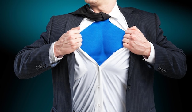 Businessman tears shirt on himself to show that he is superman\
isolated on background