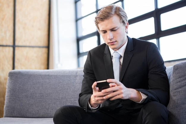 Businessman text messaging on mobile phone in office