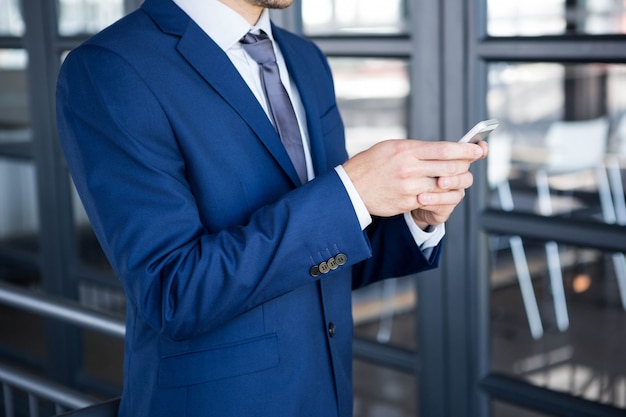 Обмен текстовыми сообщениями бизнесмена на smartphone в офисе