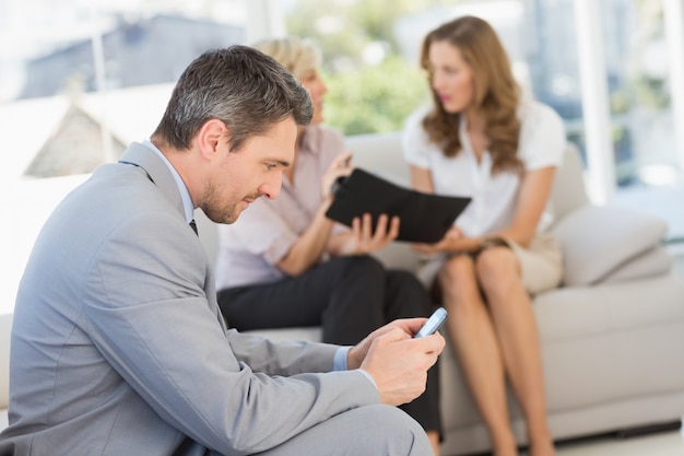 Businessman text messaging with colleagues sitting at home