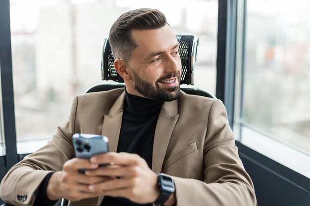 Photo businessman texting on the cellphone in the office and looking out the window