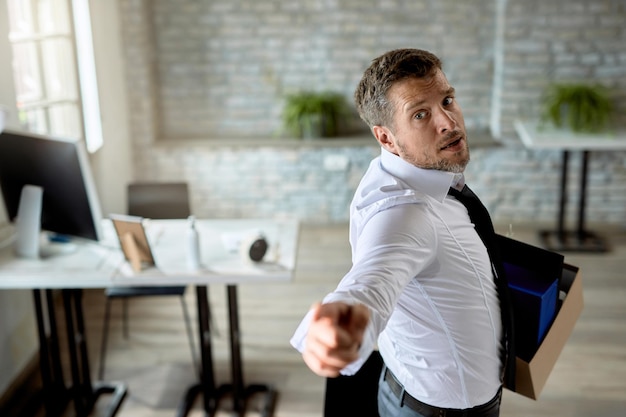 Businessman threatening to someone while carrying his belonging and leaving the office after being fired