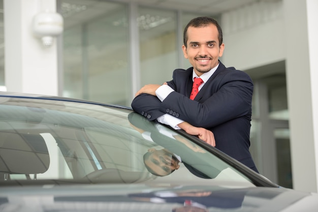 Businessman in a tie and suit stands and smiles.