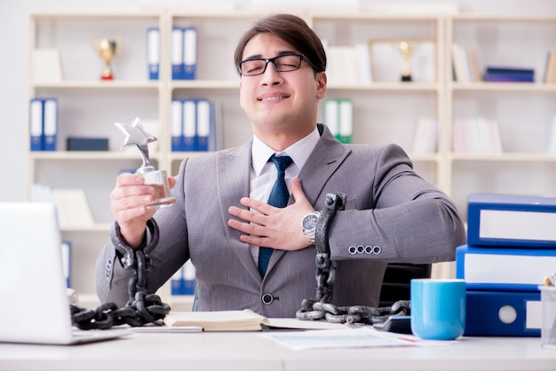 Businessman tied with chains to his work