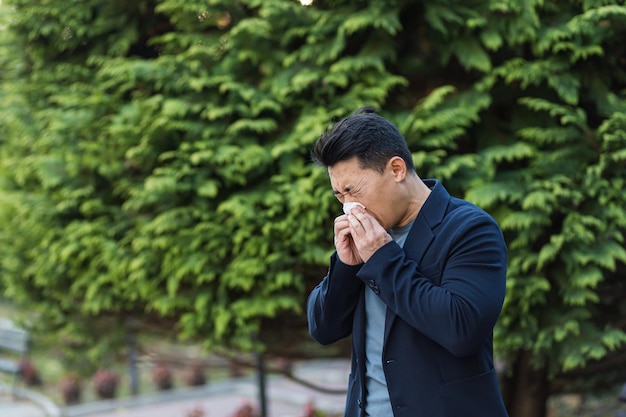 Businessman tired and sick asian man sneezes and coughs on the street, allergic reaction