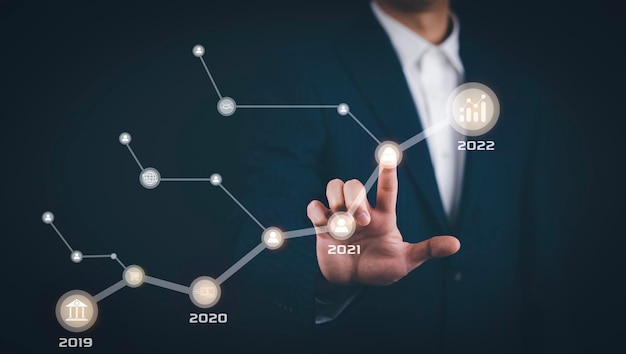 Businessman touch line arrow with number 2022 on the graph chart of stock market Technology